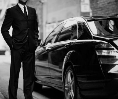 A man in a suit standing next to a car.