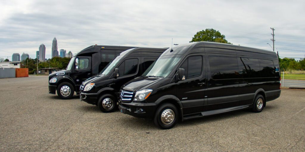 Row of black Mercedes Sprinter vans parked in gravel lot.
