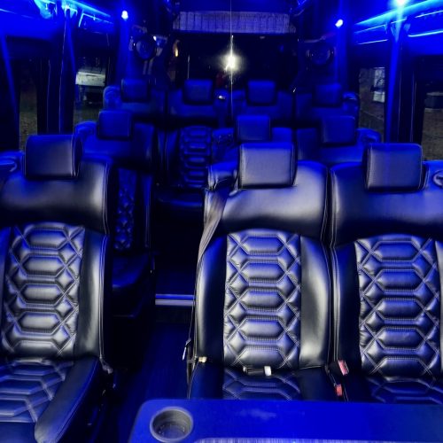 Blue-lit van interior with high-back leather seats and glowing trim.